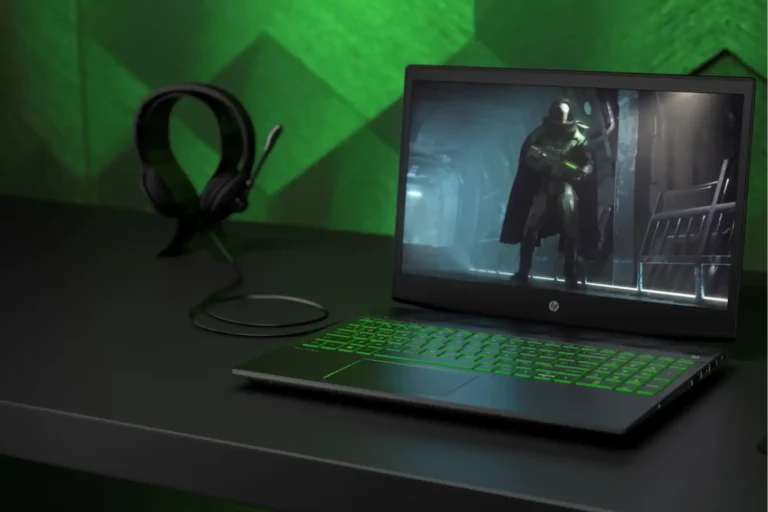 HP Pavilion Gaming Laptop with green backlit keyboard and gaming headset on a desk at YourShoppy.com in Koramangala.