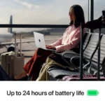 Woman using a Space Black Apple MacBook Pro 14-inch laptop at an airport with an airplane outside the window.