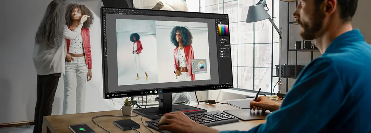 Photographer editing images on a Lenovo monitor