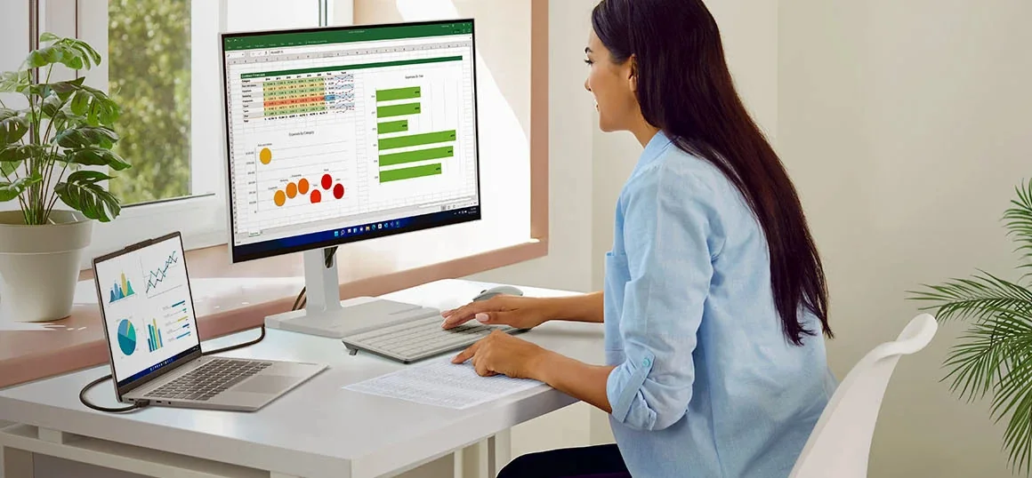 Woman working on a laptop connected to a Lenovo monitor at home